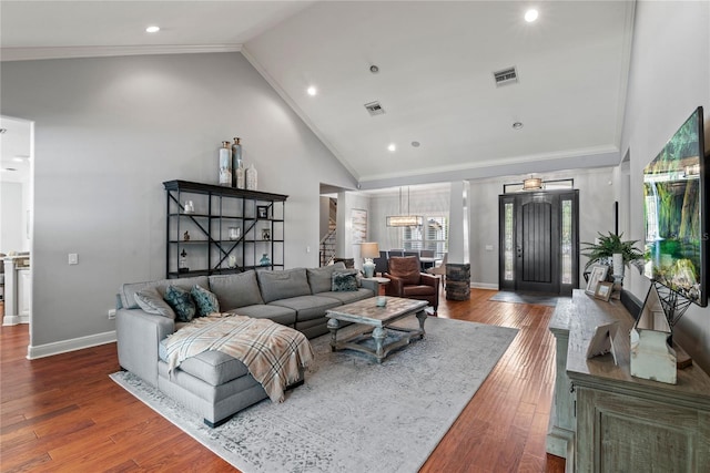 living area featuring wood finished floors, visible vents, high vaulted ceiling, and ornamental molding