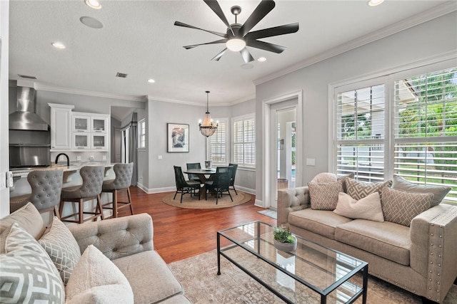 living room featuring recessed lighting, wood finished floors, visible vents, baseboards, and ceiling fan with notable chandelier