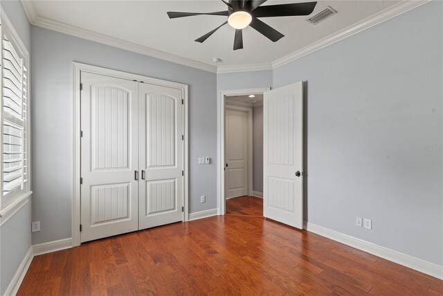 unfurnished bedroom with a closet, wood finished floors, visible vents, and ornamental molding