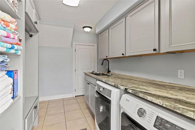 laundry area featuring a sink, washer and clothes dryer, baseboards, cabinet space, and light tile patterned floors