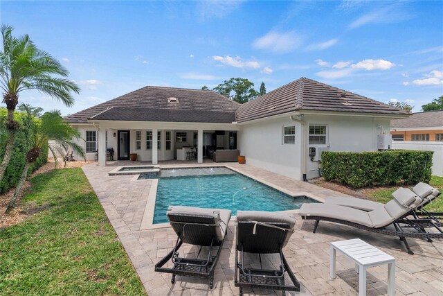 rear view of property with a tile roof, a patio area, outdoor lounge area, stucco siding, and a pool with connected hot tub