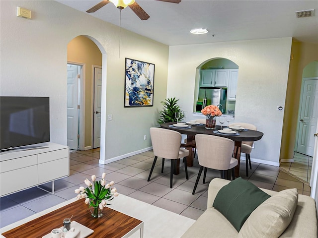 living area with light tile patterned floors, visible vents, arched walkways, and ceiling fan