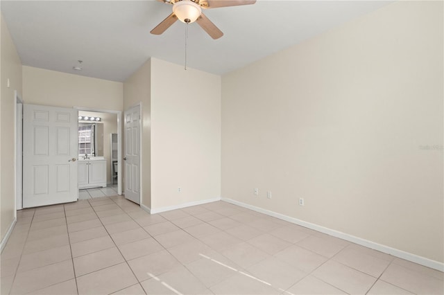 unfurnished room with ceiling fan, baseboards, and light tile patterned floors