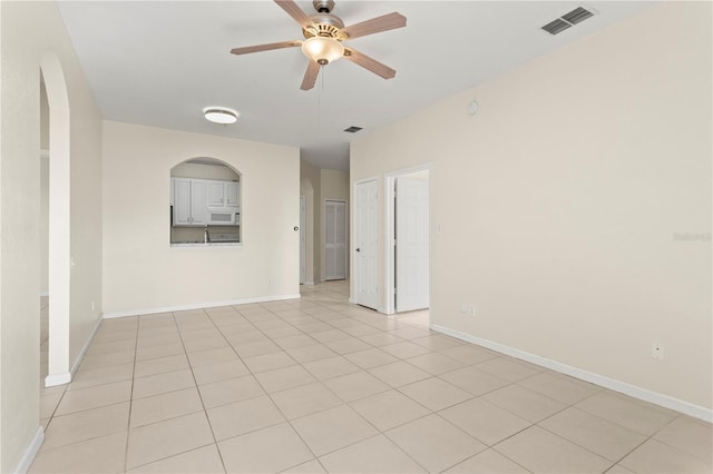 unfurnished room with baseboards, a ceiling fan, visible vents, and light tile patterned floors