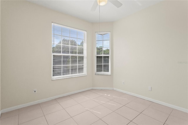 empty room with a ceiling fan, baseboards, and light tile patterned floors