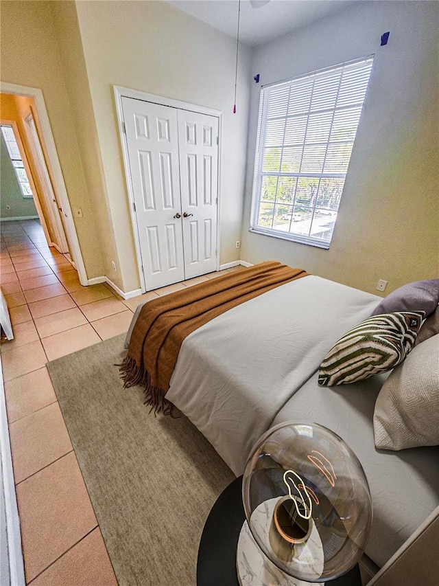 tiled bedroom featuring baseboards and a closet