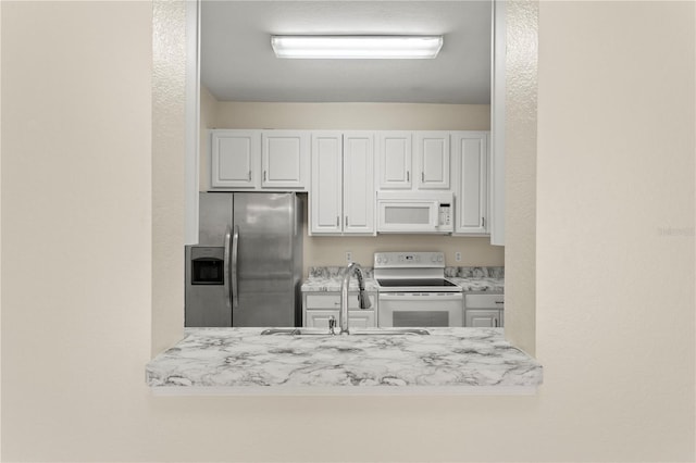 kitchen with light countertops, white cabinets, a sink, and white appliances