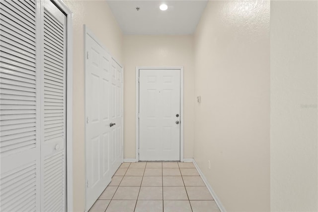hall featuring baseboards and light tile patterned floors