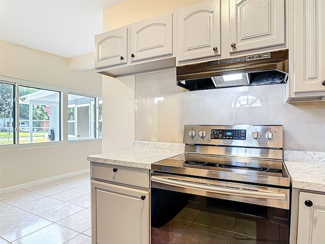 4514 Southmore Dr, Orlando, FL 32812 - kitchen with under cabinet range hood, light tile patterned floors, stainless steel electric range oven, light stone counters, and baseboards