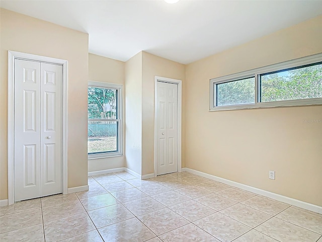 4514 Southmore Dr, Orlando, FL 32812 - unfurnished bedroom with light tile patterned flooring, multiple windows, two closets, and baseboards