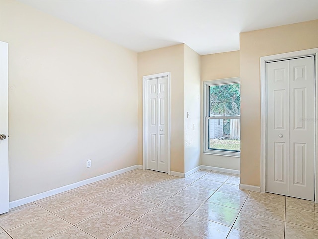 4514 Southmore Dr, Orlando, FL 32812 - unfurnished bedroom with light tile patterned flooring, two closets, and baseboards