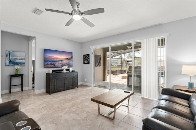living area featuring baseboards, a ceiling fan, visible vents, and light tile patterned floors
