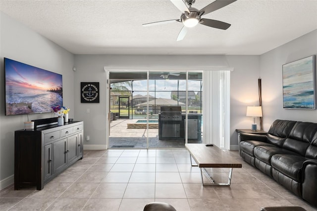 living area featuring a textured ceiling, a ceiling fan, baseboards, and light tile patterned floors