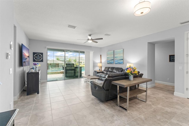 living room with ceiling fan, visible vents, and light tile patterned floors