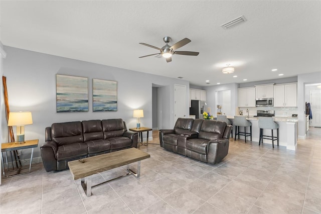 living room featuring visible vents, a ceiling fan, baseboards, and light tile patterned floors