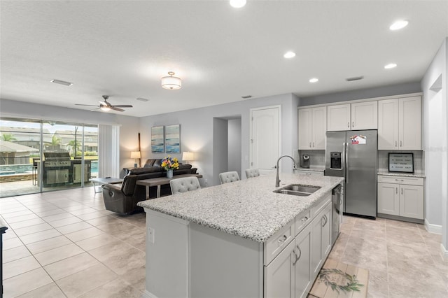 kitchen with recessed lighting, light stone countertops, appliances with stainless steel finishes, and a sink
