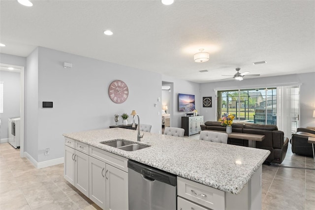 kitchen featuring stainless steel dishwasher, a sink, an island with sink, open floor plan, and ceiling fan