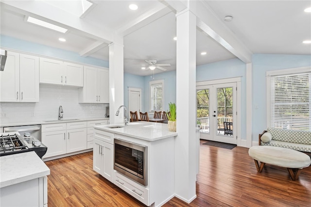 404 N Clara Ave, Deland, FL 32720 - kitchen featuring appliances with stainless steel finishes, beam ceiling, tasteful backsplash, light wood finished floors, and white cabinetry