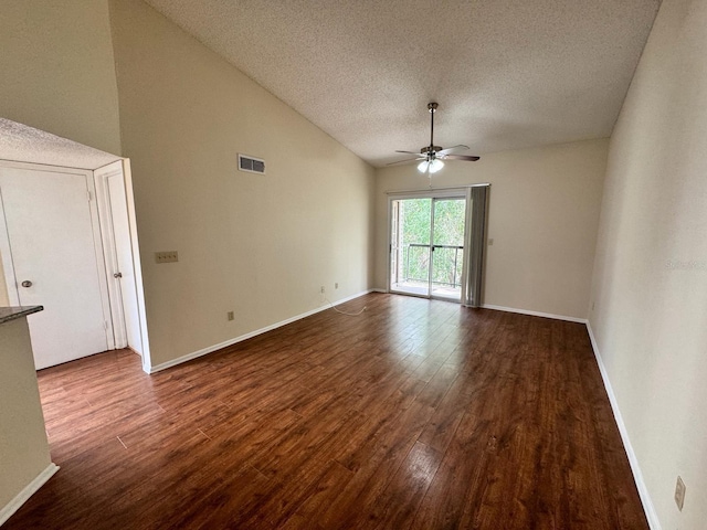 empty room with dark wood finished floors, lofted ceiling, visible vents, a textured ceiling, and ceiling fan