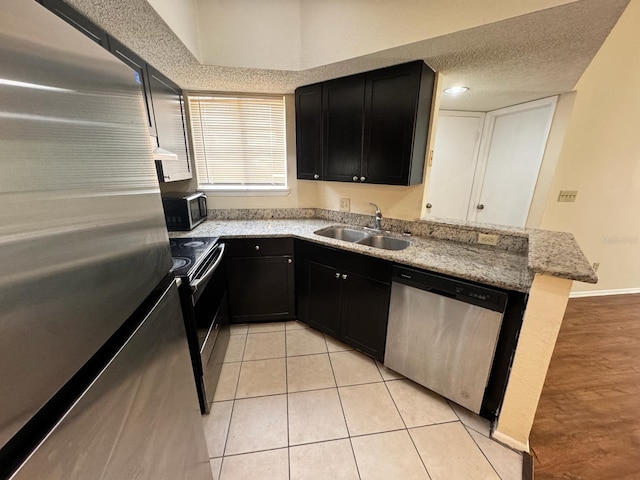 kitchen featuring dark cabinetry, stainless steel appliances, a peninsula, and a sink