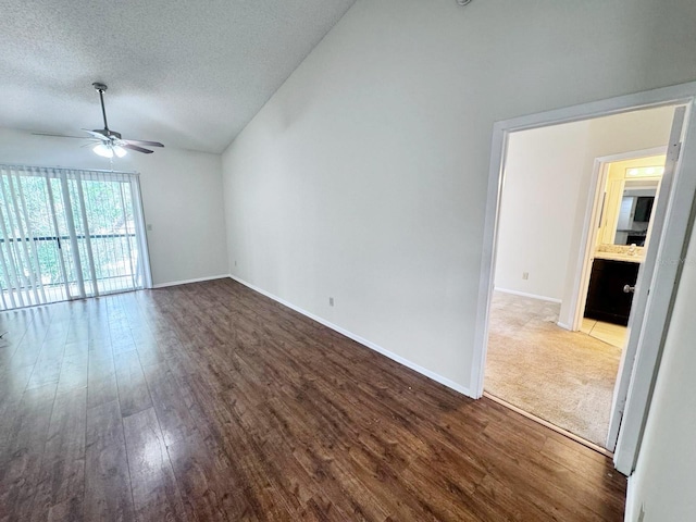 spare room with a textured ceiling, baseboards, lofted ceiling, wood finished floors, and ceiling fan