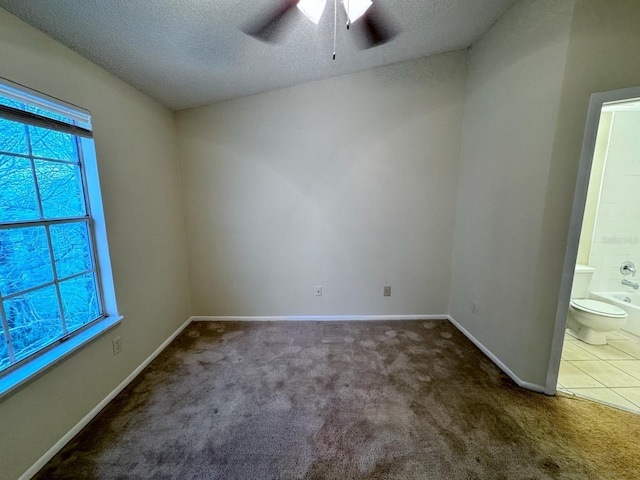 carpeted empty room with ceiling fan, a wealth of natural light, and a textured ceiling