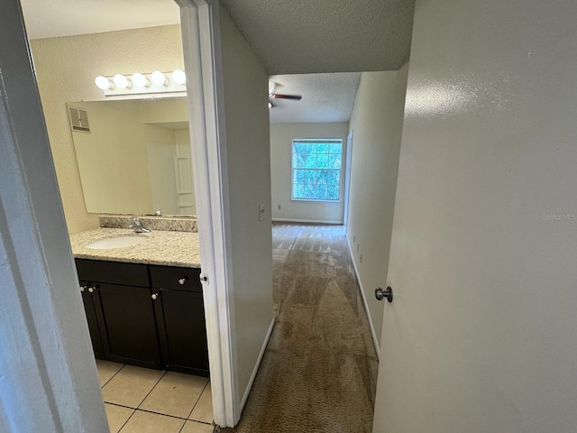 bathroom featuring a textured ceiling, visible vents, baseboards, ceiling fan, and vanity