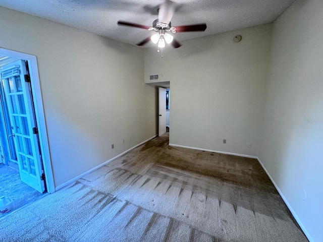 carpeted spare room with ceiling fan, baseboards, a textured ceiling, and visible vents