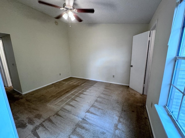 carpeted empty room with a ceiling fan, baseboards, and a textured ceiling