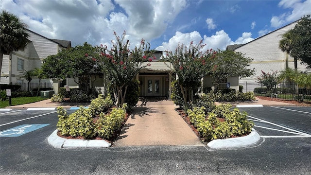 view of front of property featuring uncovered parking, fence, and french doors