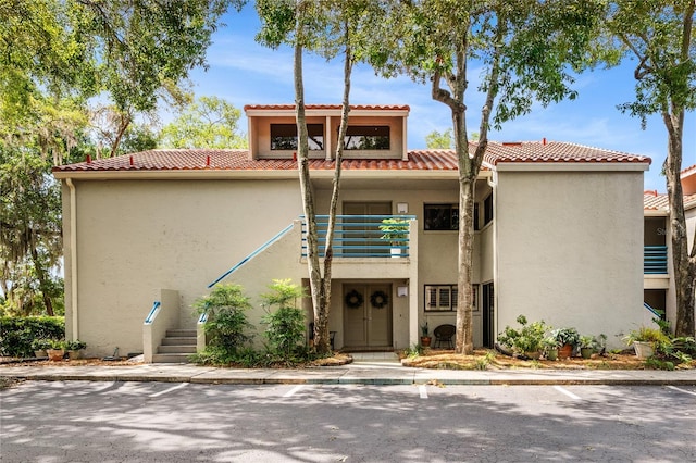 view of front of home with a balcony, stucco siding, and a tiled roof