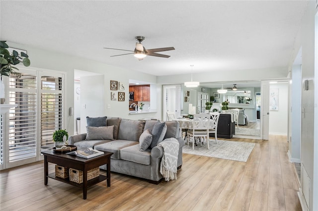living room featuring ceiling fan and light wood finished floors