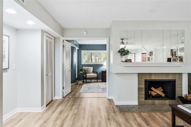 living room featuring wood finished floors, baseboards, a brick fireplace, and recessed lighting
