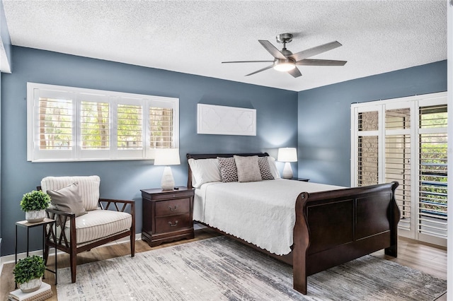 bedroom with wood finished floors, a textured ceiling, and ceiling fan