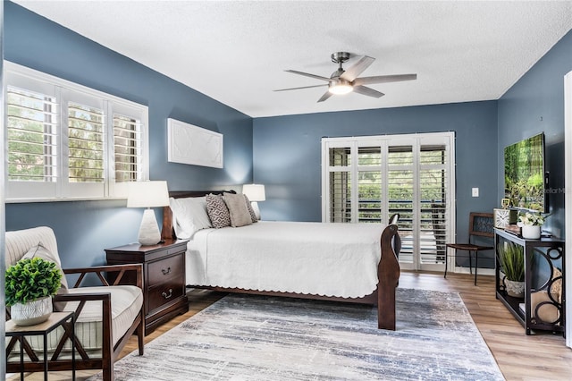 bedroom with a textured ceiling, access to exterior, and wood finished floors