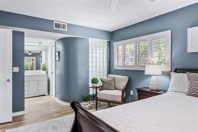 bedroom featuring light wood finished floors, a textured ceiling, and baseboards