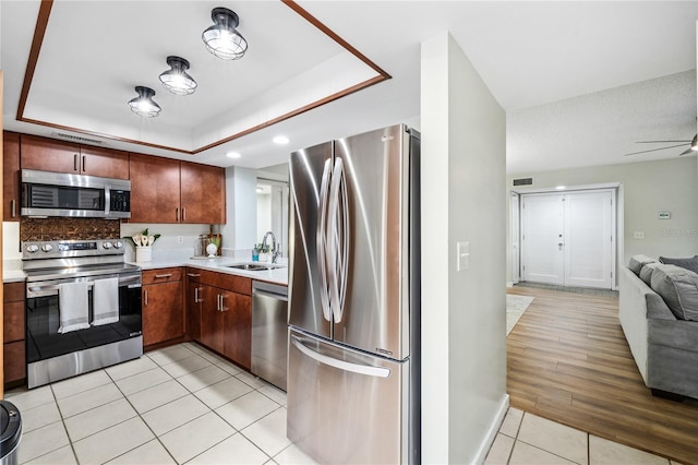 kitchen featuring stainless steel appliances, a sink, open floor plan, light tile patterned flooring, and light countertops