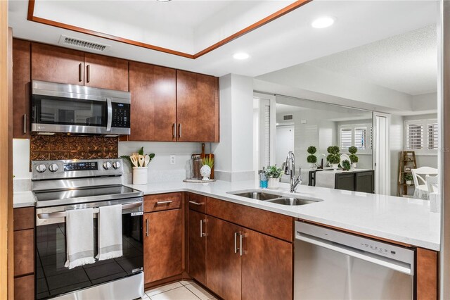 kitchen featuring appliances with stainless steel finishes, a sink, light countertops, recessed lighting, and light tile patterned floors