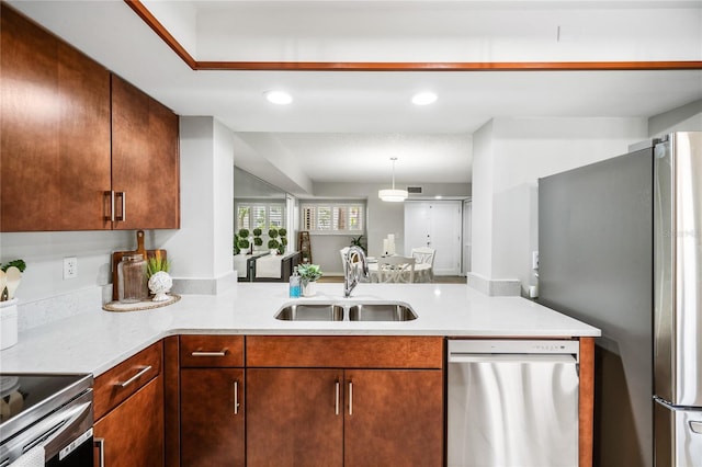 kitchen featuring a sink, stainless steel appliances, a peninsula, recessed lighting, and hanging light fixtures