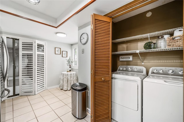 washroom with washing machine and clothes dryer, light tile patterned floors, and baseboards