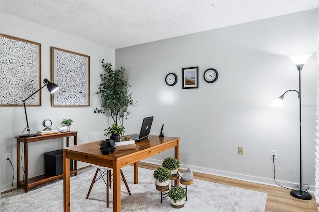 office space with light wood finished floors, baseboards, and a textured ceiling