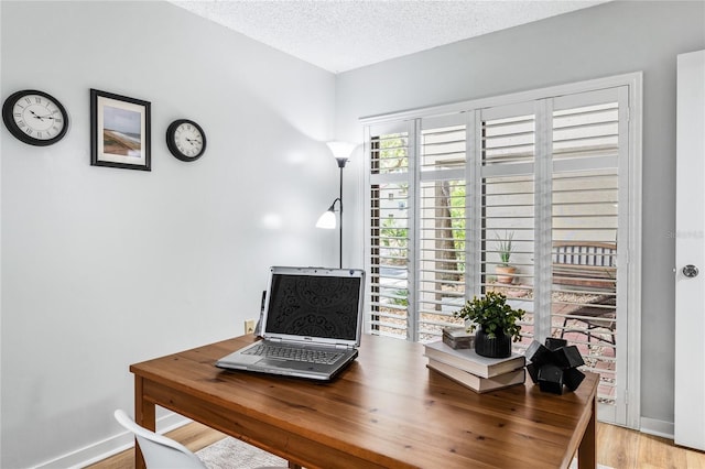 office space featuring baseboards, a textured ceiling, and wood finished floors