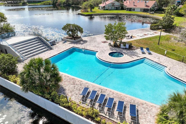 community pool featuring a water view, a hot tub, and a patio area
