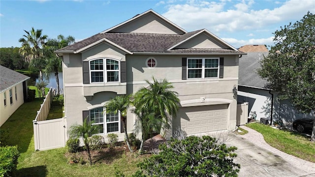 view of front of property with stucco siding, fence, driveway, a front lawn, and an attached garage