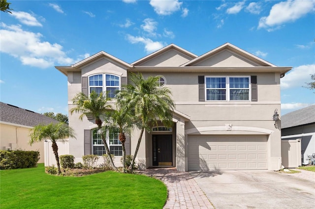 traditional-style home featuring a front yard, driveway, a garage, and stucco siding