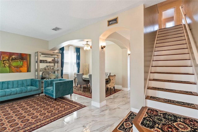 living area featuring visible vents, stairs, marble finish floor, and arched walkways