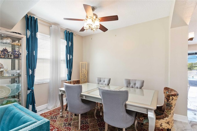 dining space with a ceiling fan and baseboards