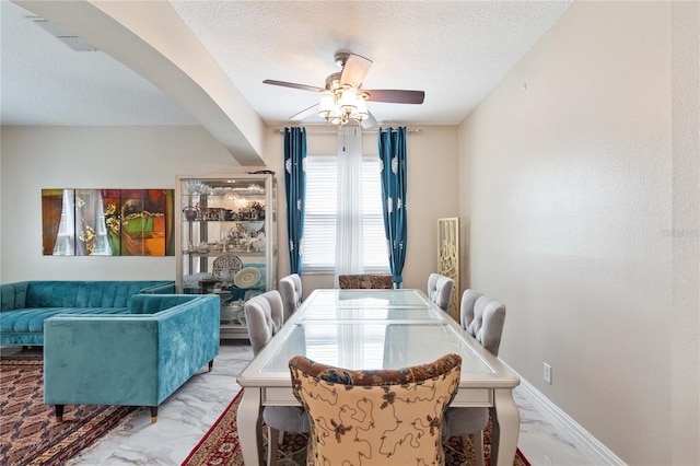 dining area with marble finish floor, ceiling fan, a textured ceiling, and visible vents