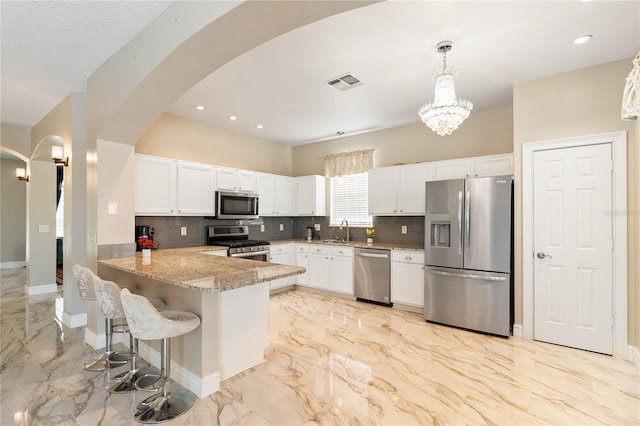 kitchen with a sink, a notable chandelier, visible vents, arched walkways, and appliances with stainless steel finishes