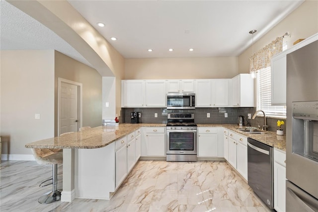 kitchen featuring appliances with stainless steel finishes, a peninsula, marble finish floor, and a sink